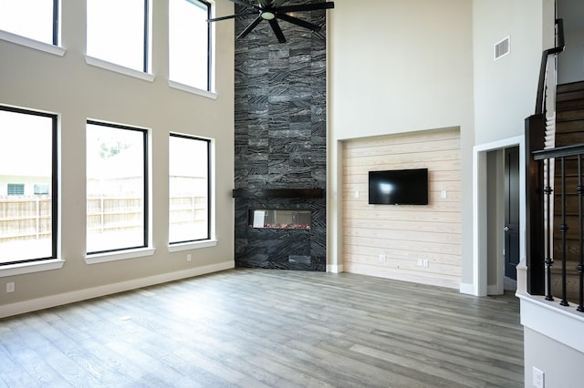 unfurnished living room featuring a fireplace, hardwood / wood-style floors, and a high ceiling