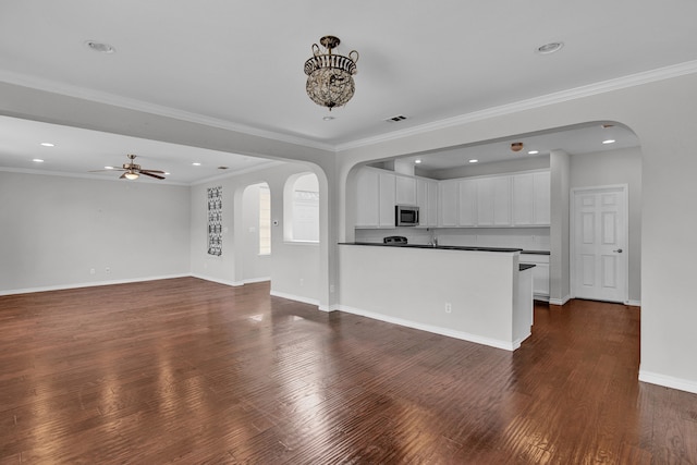 unfurnished living room featuring ceiling fan, crown molding, and dark wood-type flooring