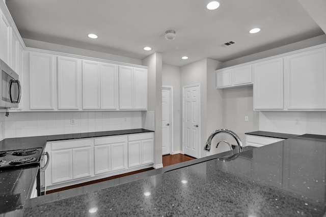 kitchen featuring dark stone countertops, white cabinetry, backsplash, and dark hardwood / wood-style floors