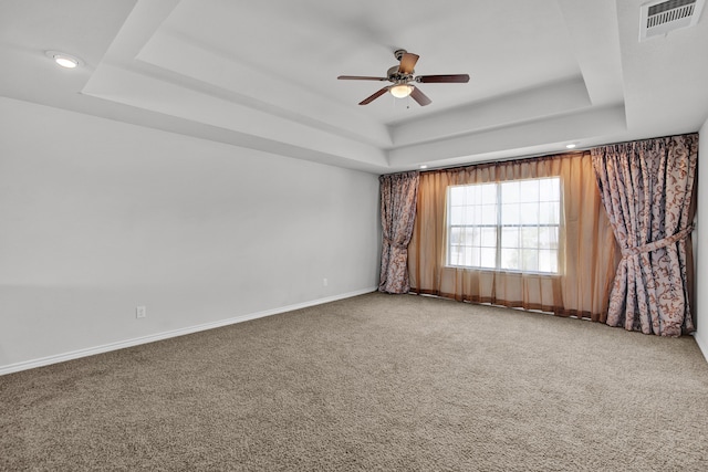 carpeted spare room with ceiling fan and a raised ceiling