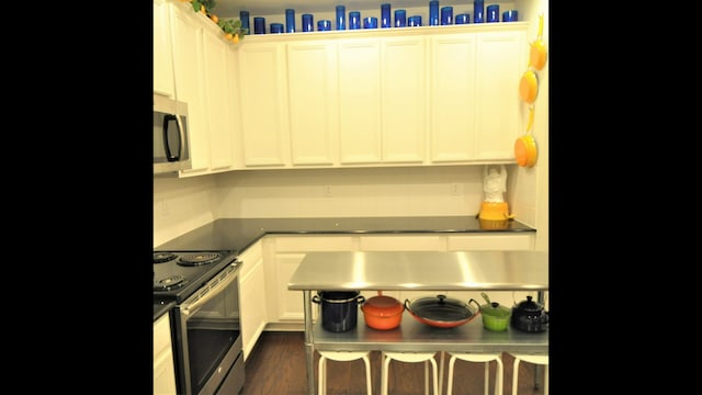 kitchen featuring stainless steel appliances, white cabinetry, and dark hardwood / wood-style flooring