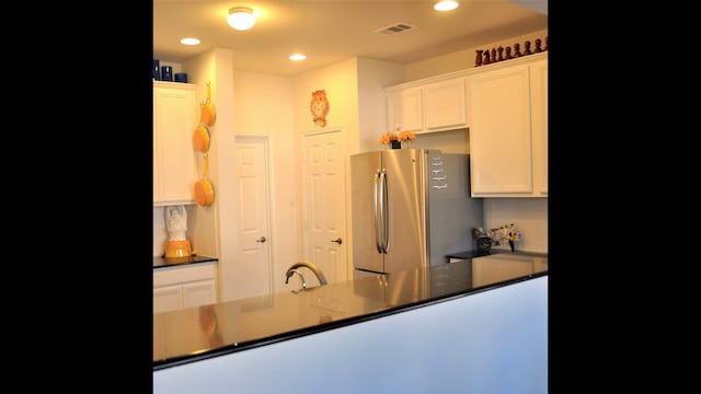 kitchen featuring white cabinets, stainless steel refrigerator, sink, and backsplash