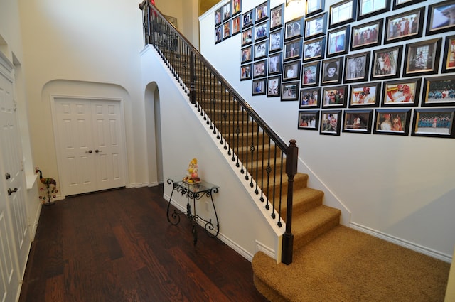 staircase featuring hardwood / wood-style flooring and a towering ceiling