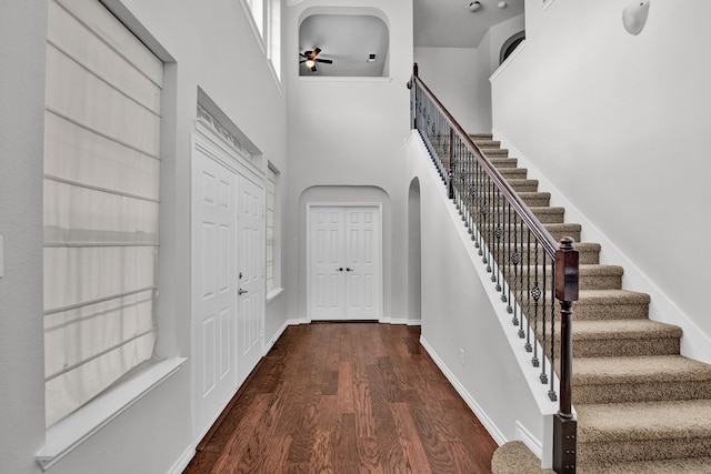 entryway featuring a towering ceiling, dark hardwood / wood-style floors, and ceiling fan