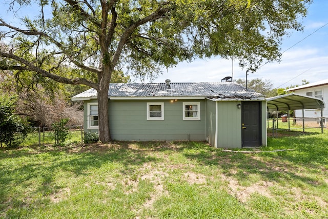 rear view of property with a carport and a lawn