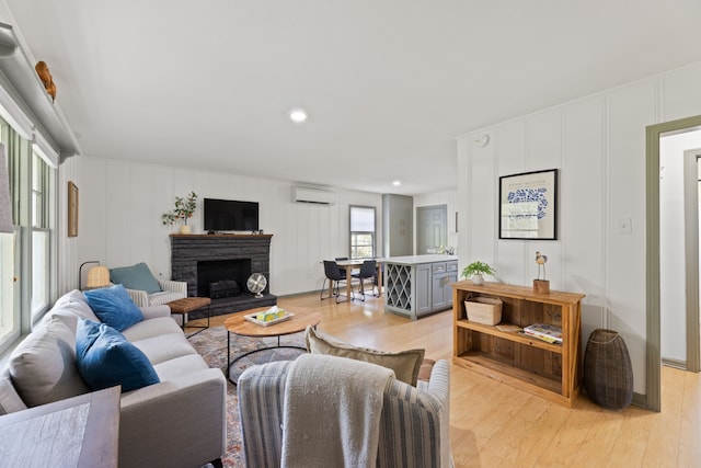 living room featuring a fireplace, light hardwood / wood-style flooring, and a wall unit AC