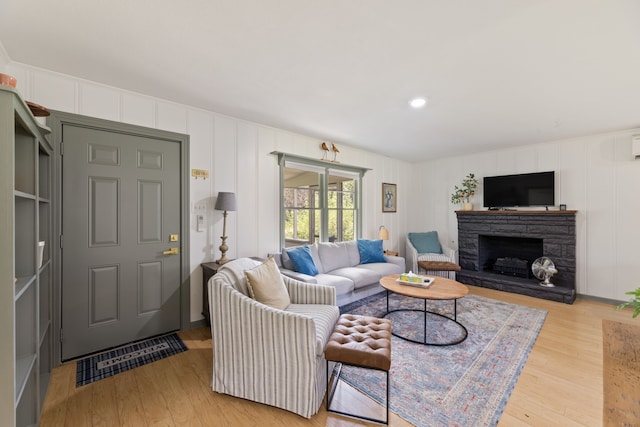 living room featuring a stone fireplace and light hardwood / wood-style flooring