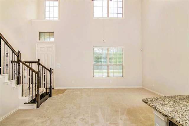 carpeted foyer entrance with a towering ceiling