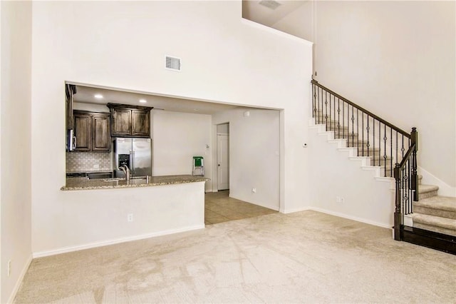 kitchen featuring tasteful backsplash, a high ceiling, light colored carpet, sink, and stainless steel fridge with ice dispenser