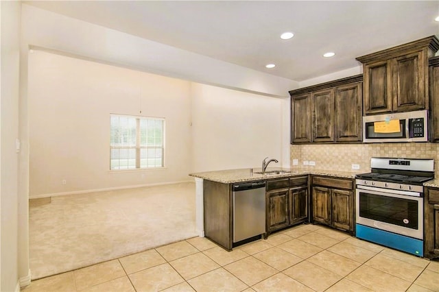 kitchen with appliances with stainless steel finishes, light colored carpet, light stone counters, and sink