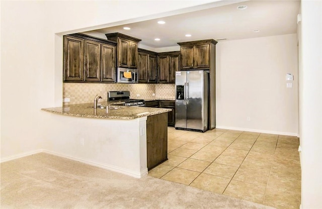 kitchen with stainless steel appliances, light stone counters, light colored carpet, and sink