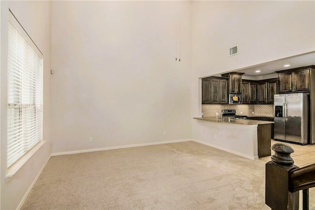 kitchen with a wealth of natural light, kitchen peninsula, light carpet, and appliances with stainless steel finishes