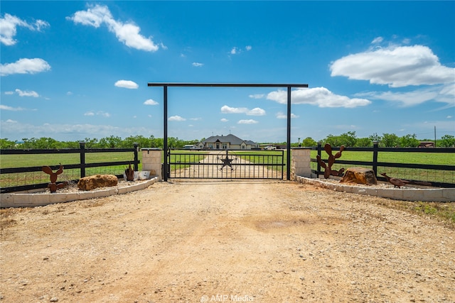 view of gate with a rural view and a lawn