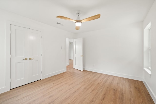 unfurnished bedroom with ceiling fan, a closet, and light wood-type flooring