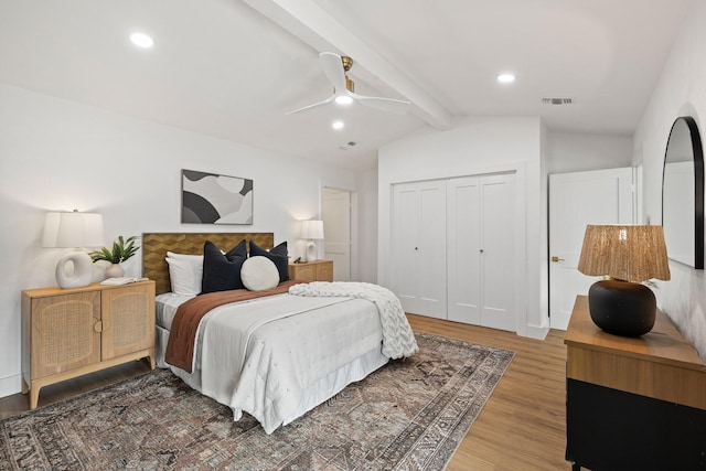 bedroom with ceiling fan, lofted ceiling with beams, wood-type flooring, and a closet