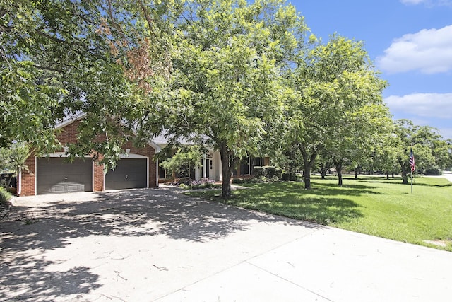 view of property hidden behind natural elements with a garage and a front yard