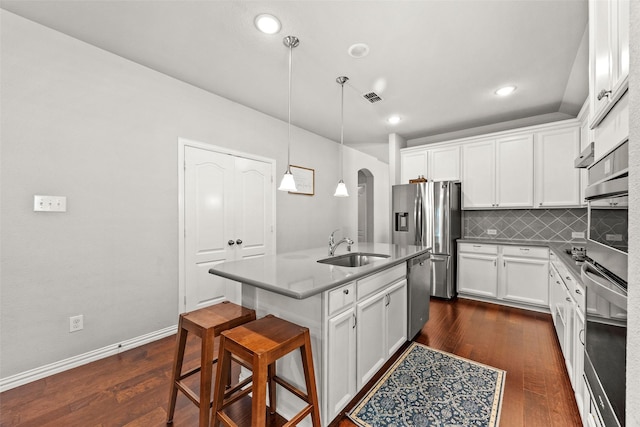 kitchen featuring decorative backsplash, appliances with stainless steel finishes, a kitchen island with sink, pendant lighting, and white cabinets