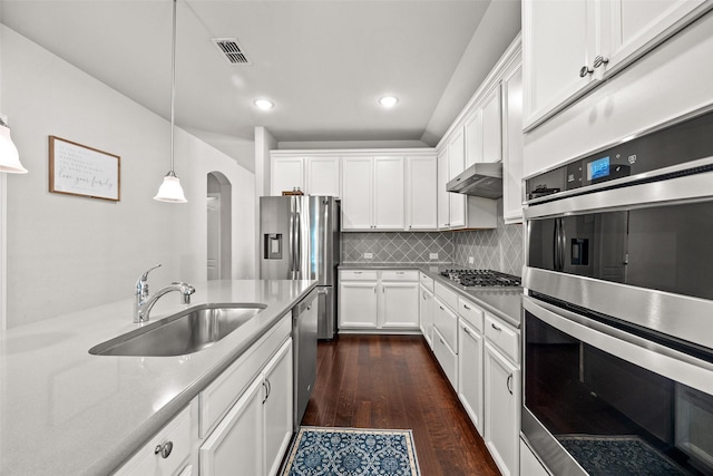 kitchen featuring exhaust hood, white cabinets, hanging light fixtures, sink, and appliances with stainless steel finishes