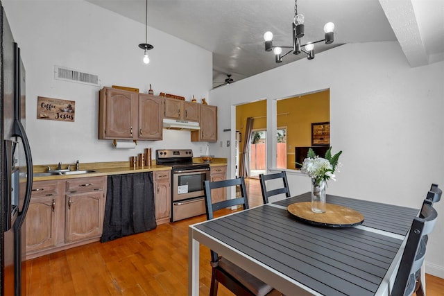 kitchen featuring black refrigerator, light wood-type flooring, hanging light fixtures, electric range, and a chandelier