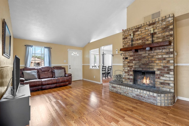 living room featuring lofted ceiling, a fireplace, and wood-type flooring