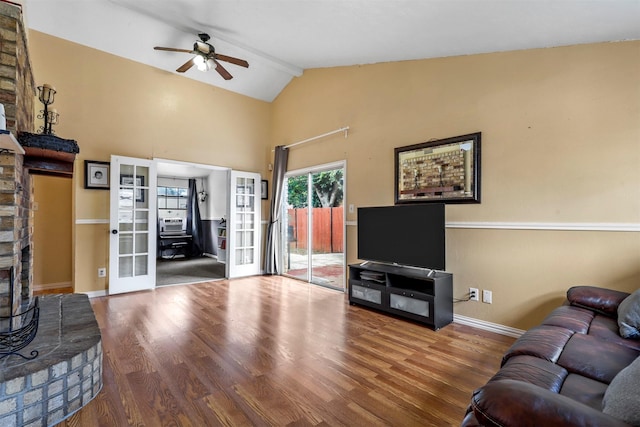 living room featuring hardwood / wood-style flooring, french doors, a brick fireplace, ceiling fan, and vaulted ceiling with beams