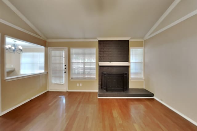 unfurnished living room featuring crown molding, hardwood / wood-style flooring, lofted ceiling, and a brick fireplace