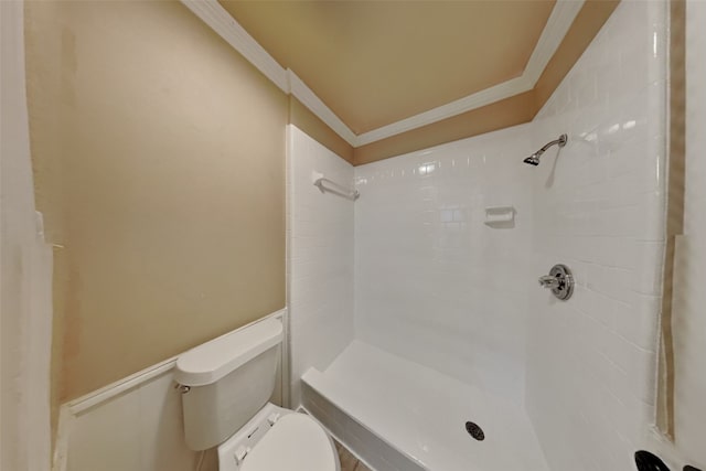 bathroom with a tile shower, ornamental molding, and toilet