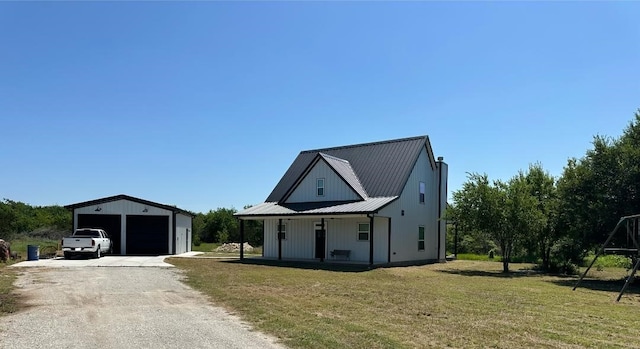 modern inspired farmhouse featuring a garage, an outdoor structure, covered porch, and a front yard