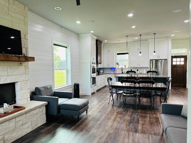 dining space with a fireplace, dark hardwood / wood-style floors, sink, and a wealth of natural light