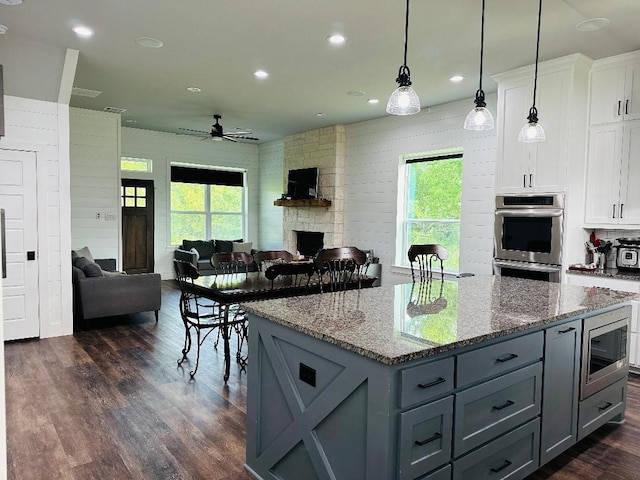 kitchen featuring appliances with stainless steel finishes, decorative light fixtures, dark stone counters, and white cabinets