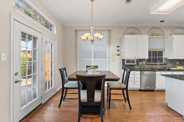 dining room with light wood-style floors, visible vents, crown molding, and an inviting chandelier