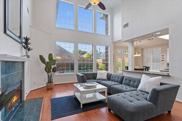 living area with a fireplace, wood finished floors, visible vents, and baseboards