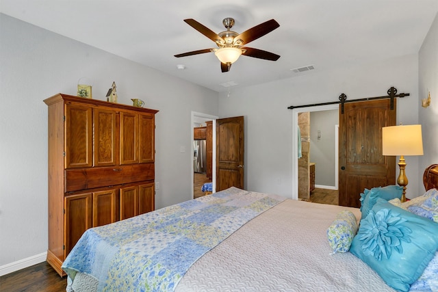 bedroom with ceiling fan, dark hardwood / wood-style flooring, and a barn door