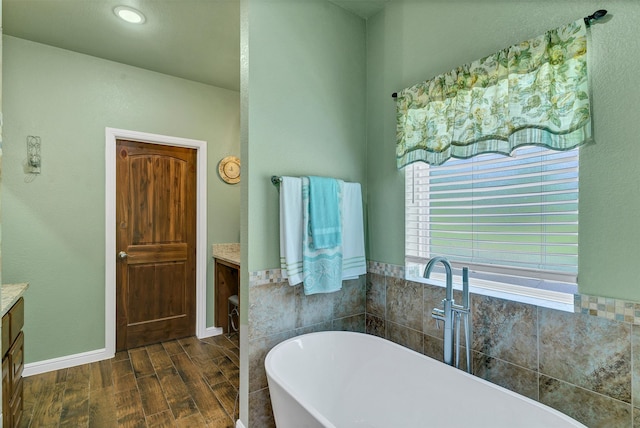 bathroom with wood-type flooring, a tub to relax in, and vanity