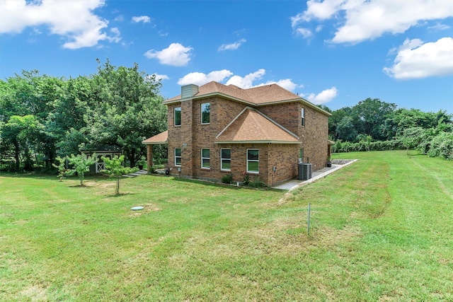 back of property with central AC unit and a yard