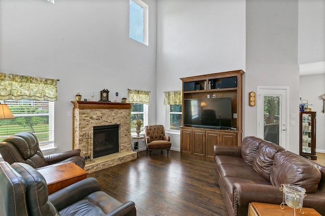 living room featuring a towering ceiling, a fireplace, plenty of natural light, and dark wood-type flooring