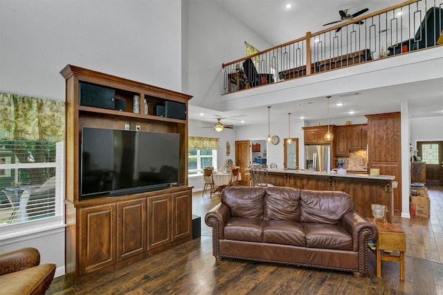 living room with ceiling fan, dark hardwood / wood-style floors, and a towering ceiling