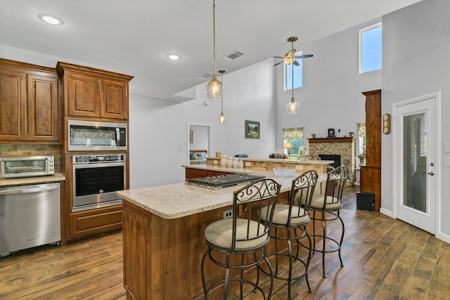 kitchen featuring appliances with stainless steel finishes, ceiling fan, dark hardwood / wood-style flooring, and a spacious island