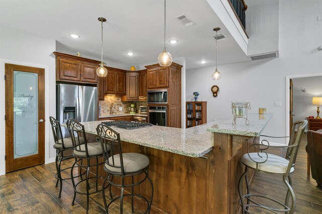 kitchen featuring dark hardwood / wood-style flooring, tasteful backsplash, a breakfast bar, appliances with stainless steel finishes, and decorative light fixtures