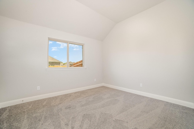 spare room with carpet and vaulted ceiling