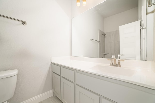 bathroom featuring vanity, toilet, and a tile shower