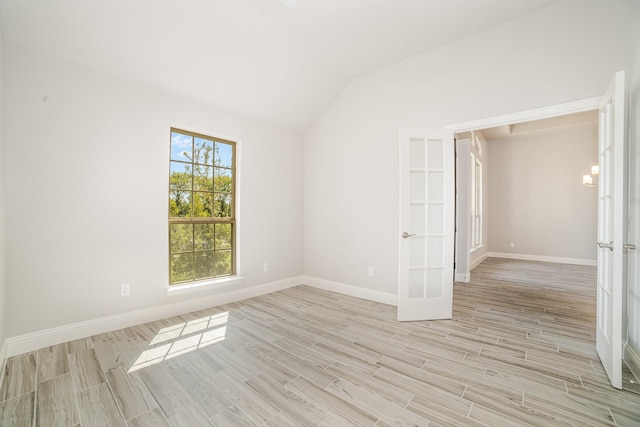 unfurnished room featuring french doors, light wood-type flooring, and lofted ceiling