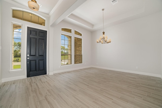 foyer entrance with light wood-type flooring, a tray ceiling, an inviting chandelier, and crown molding