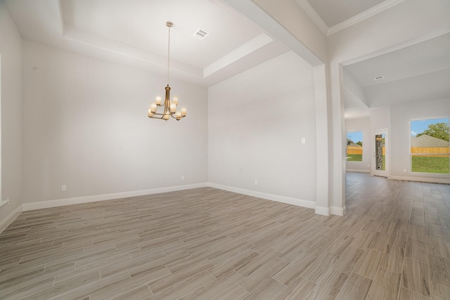 unfurnished room featuring a chandelier, a tray ceiling, light hardwood / wood-style flooring, and ornamental molding