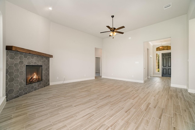 unfurnished living room with ceiling fan, light wood-type flooring, and a fireplace