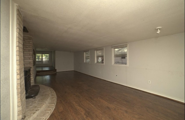 unfurnished living room featuring a textured ceiling and dark wood-type flooring