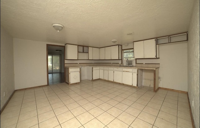 kitchen featuring white cabinets, light tile patterned flooring, and a textured ceiling