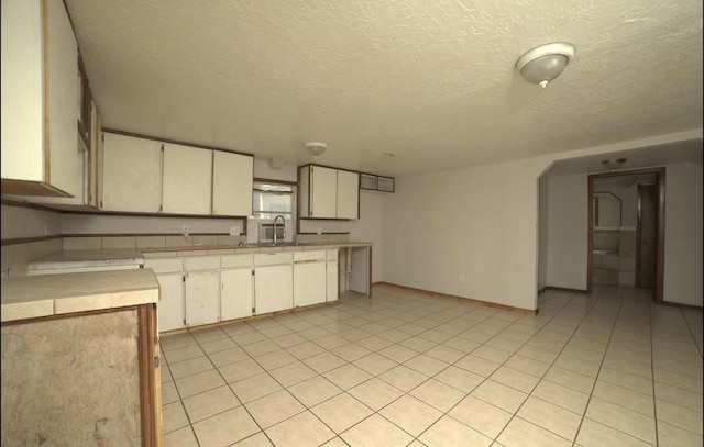 kitchen featuring light tile patterned flooring, a textured ceiling, and sink