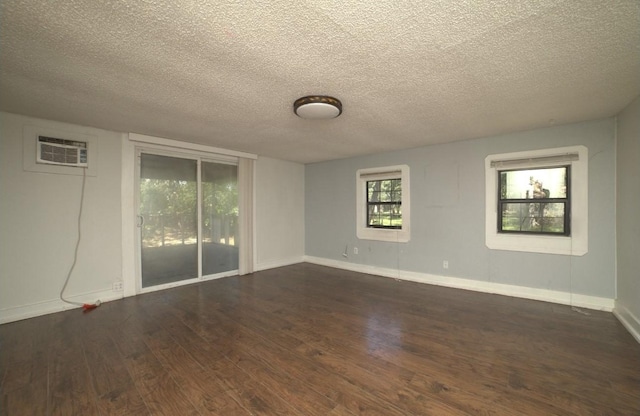 unfurnished room featuring dark hardwood / wood-style flooring, a textured ceiling, and a wall mounted AC