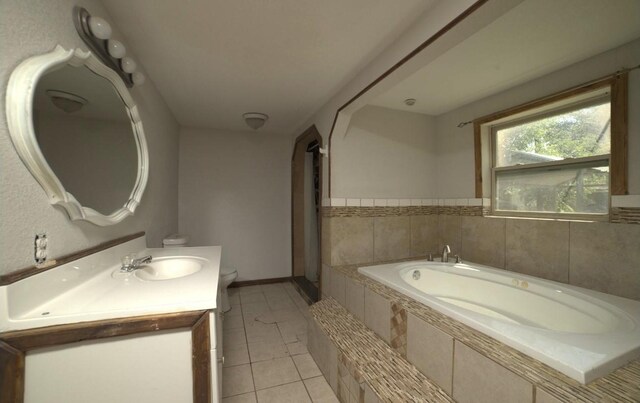 bathroom featuring tile patterned flooring, vanity, tiled bath, and toilet